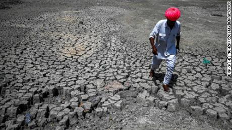 A villager walks through a dried-out pond on a hot summer day at Bandai village in Pali district on May 11, 2022. 