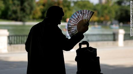 A man uses a hand fan in a park in central Madrid during a heatwave, on August 2, 2022.