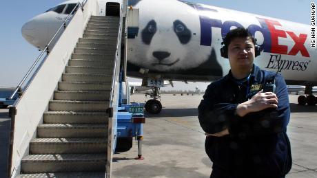 Un funcionario del aeropuerto chino se encuentra cerca del Panda Express, un avión de FedEx pintado con la cara de un panda gigante, que transporta a Ya Ya y Le Le de Beijing a Memphis el 7 de abril de 2003. 