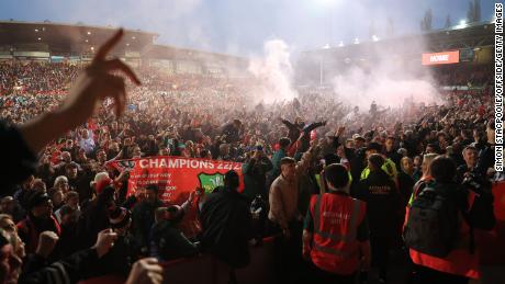 Wrexham fans celebrate on the pitch after their team beat Boreham Wood at the Racecourse Ground. 