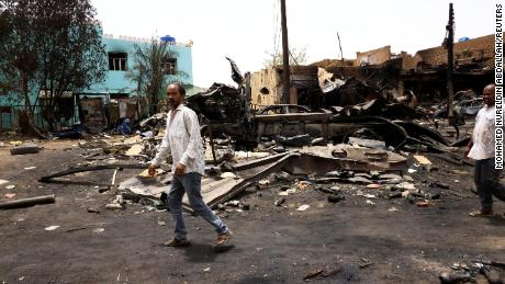 Men walk past shells on the ground near damaged buildings in Khartoum North in Sudan on Thursday, where the violence has left some locals trapped inside their homes.