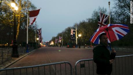 A man holds a Union-flag themed umbrella as he takes a picture on the Mall, ahead of the coronation of Britain&#39;s King Charles III.