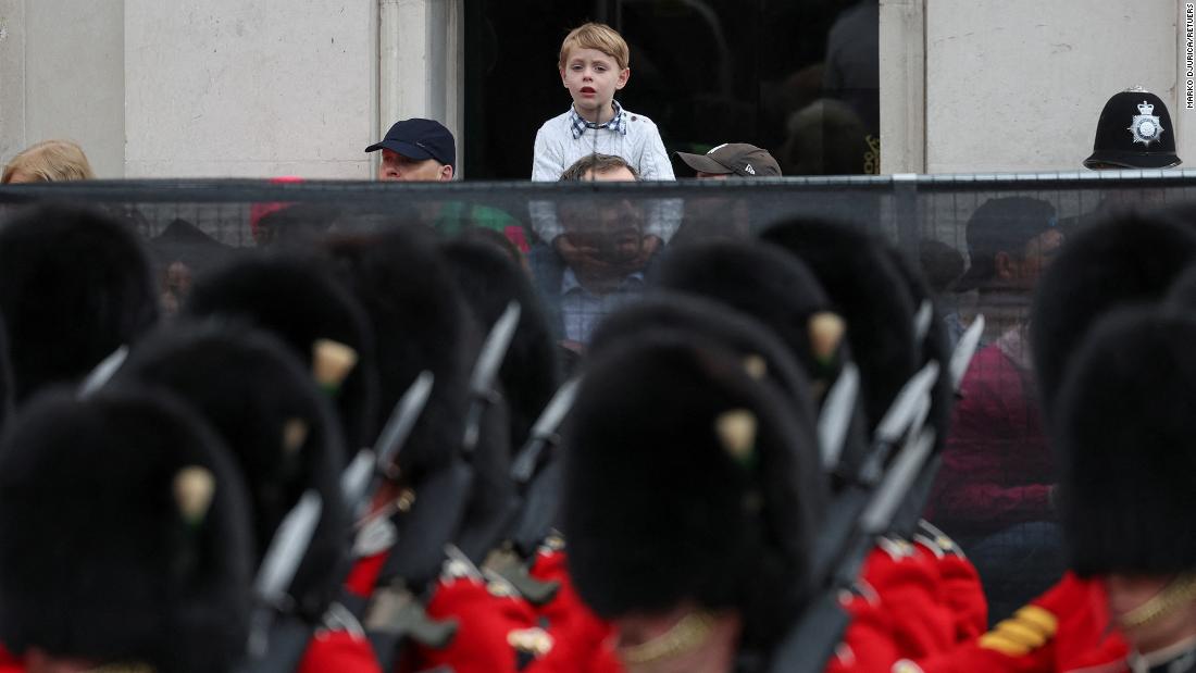 A boy watches guards march on the streets in front of Big Ben.