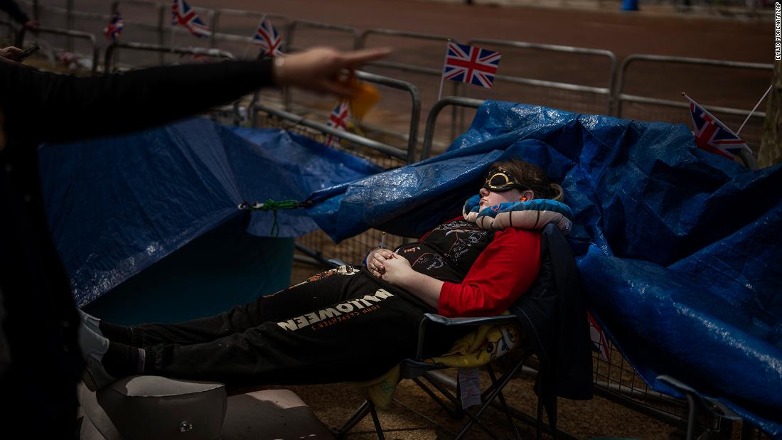 A royal fan sleeps along the procession route on Friday.