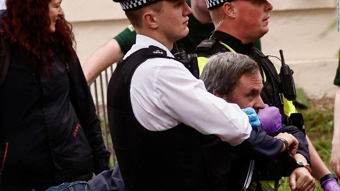 Police officers detain a protester ahead of the King&#39;s procession. &lt;a href=&quot;https://www.cnn.com/uk/live-news/king-charles-iii-coronation-ckc-intl-gbr/h_089ce3083553388e9051d6c7fd26c7b0&quot; target=&quot;_blank&quot;&gt;Several arrests were made Saturday&lt;/a&gt; as protesters gathered near the procession route.