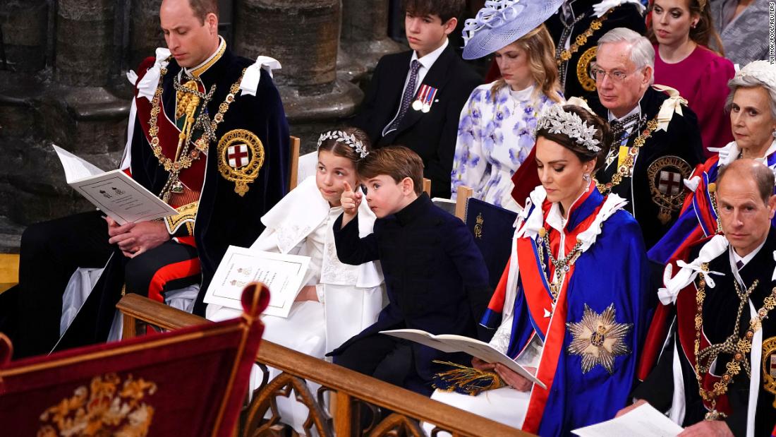 Prince Louis points out something to his sister, Princess Charlotte, during the ceremony. They are flanked by their parents, Prince William and Catherine, the Princess of Wales.