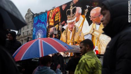 People pass in front of a screen showing an image from King Charles III coronation in Piccadilly Circus, London, following the event on May 6