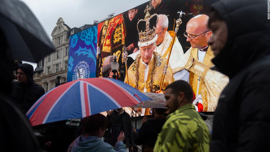 People in London&#39;s Piccadilly Circus walk past a giant screen showing an image of the King during the coronation ceremony.