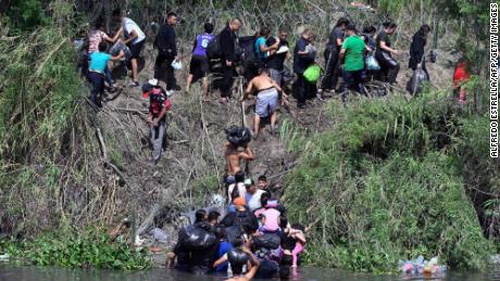 Migrants try to get to the US through the Rio Grande, which is reinforced with a barbed-wire fence, as seen from Matamoros, Mexico, on Wednesday.