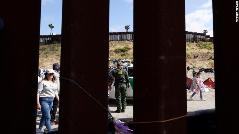 A US Border Patrol agent looks on as migrants wait to apply for asylum near San Diego on May 11.