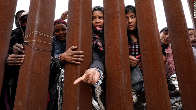 Migrants reach through a border wall for clothing handed out by volunteers near San Diego on May 12.