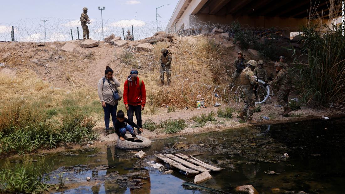 Migrants cross the Rio Bravo to return to Ciudad Juárez, Mexico, on Saturday, May 13, as members of the Texas National Guard extend razor wire at the border.
