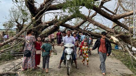 Residents walk past fallen trees in Kyauktaw in Myanmar&#39;s Rakhine state on May 15, 2023, after Cyclone Mocha crashed ashore. 