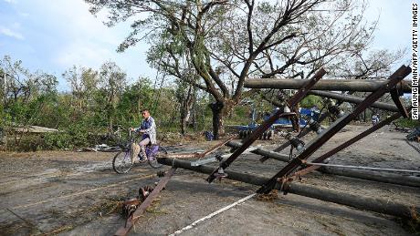 A resident drives his motorbike past fallen utility poles in Kyauktaw in Myanmar&#39;s Rakhine state on May 15, 2023, after Cyclone Mocha crashed ashore. 