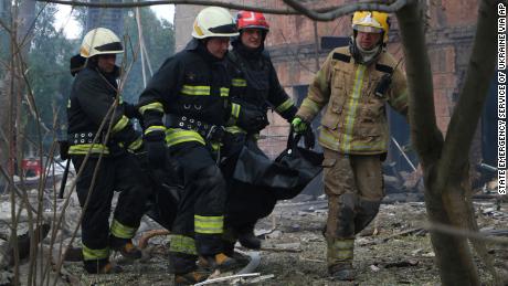 Firefighters carry a body after the deadly Russian attack in Dnipro, which left at least two people dead.
