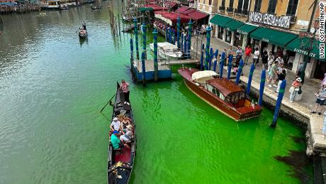 A gondola crosses Venice&#39;s historical Grand Canal as a patch of phosphorescent green liquid spreads in it, Sunday, May 28, 2023. 