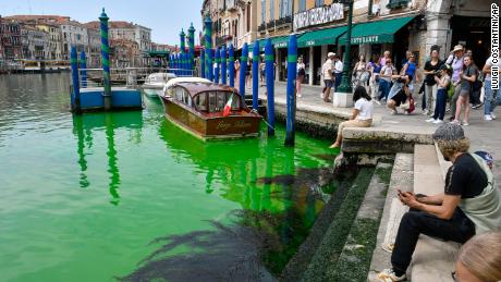 People observe Venice&#39;s historical Grand Canal as a patch of phosphorescent green liquid spreads in it,.