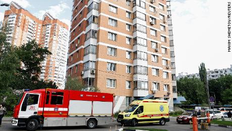 An ambulance and firefighting vehicles are parked outside a multi-storey apartment block following a reported drone attack in Moscow, Russia.