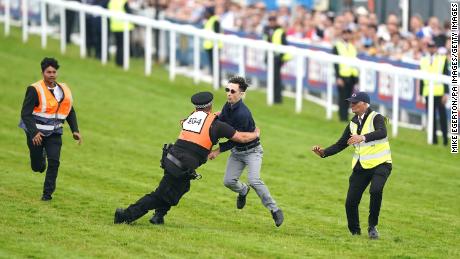 A protestor was tackled by police and stewards on the racetrack. 