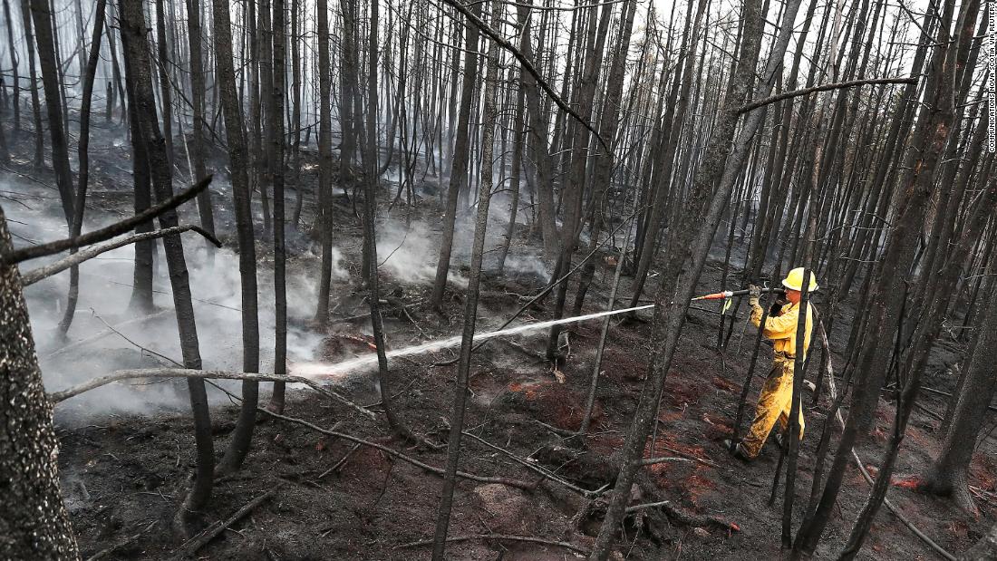 Firefighter Jason Rock sprays hot spots in the Birchtown area while tackling wildfires in Shelburne County, Nova Scotia, on June 3.