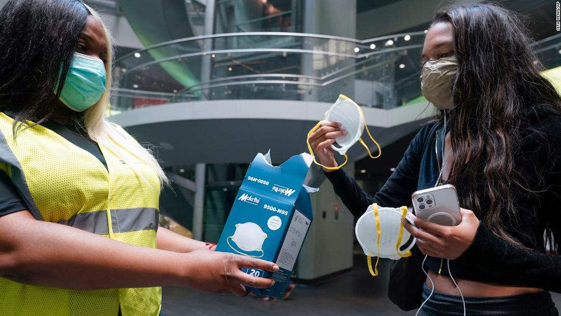 Transit employee Shanita Hancle, left, hands out masks to commuters at a subway station in New York on June 8.
