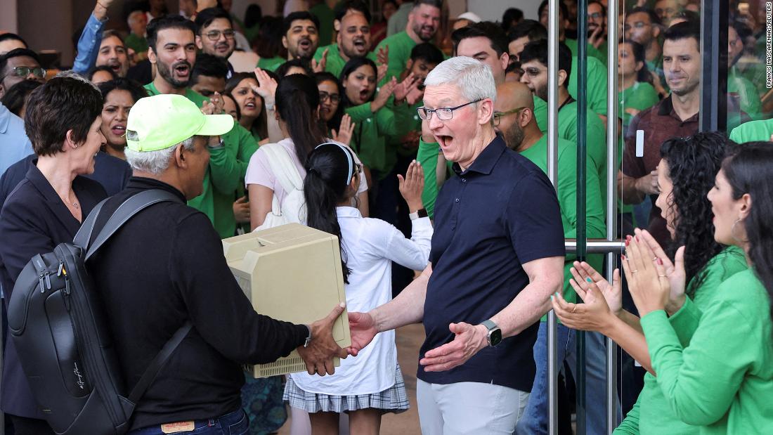 Cook reacts after seeing a Macintosh SE computer held by Sajid Moinuddin, a fan of Apple products, during the inauguration of India&#39;s first Apple retail store in Mumbai in April 2023.