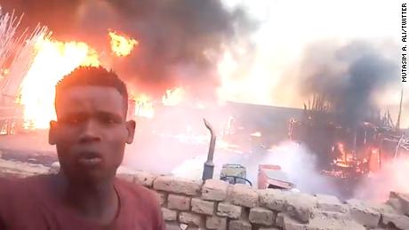 A man stands in front of the Abu Showk market as it goes up in the flames. The market services a camp for internally displaced people in Darfur&#39;s al-Fashir. 
