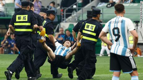 The young pitch invader is carried off the pitch by security officials during a match at the Workers&#39; Stadium in Beijing, China on June 15.