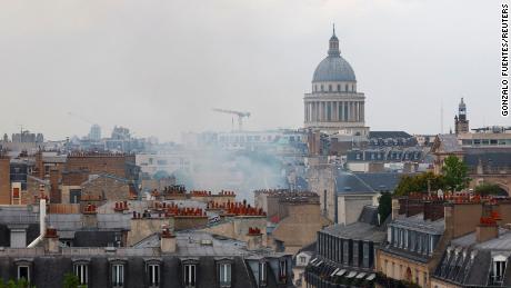 Smoke rises above rooftops with the Pantheon in the background.