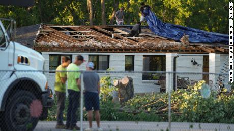Workers put a tarp over a damaged roof after a reported tornado touched down in Johnson County, Indiana, Sunday. 