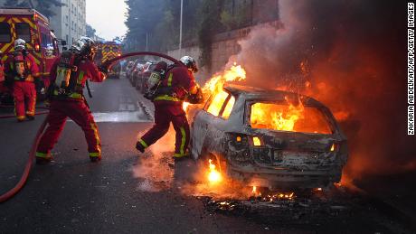 Firefighters work to put out a burning car at a protest in Nanterre, west of Paris, on June 27.