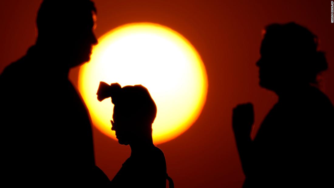 People are silhouetted against the setting sun in Kansas City on June 23.