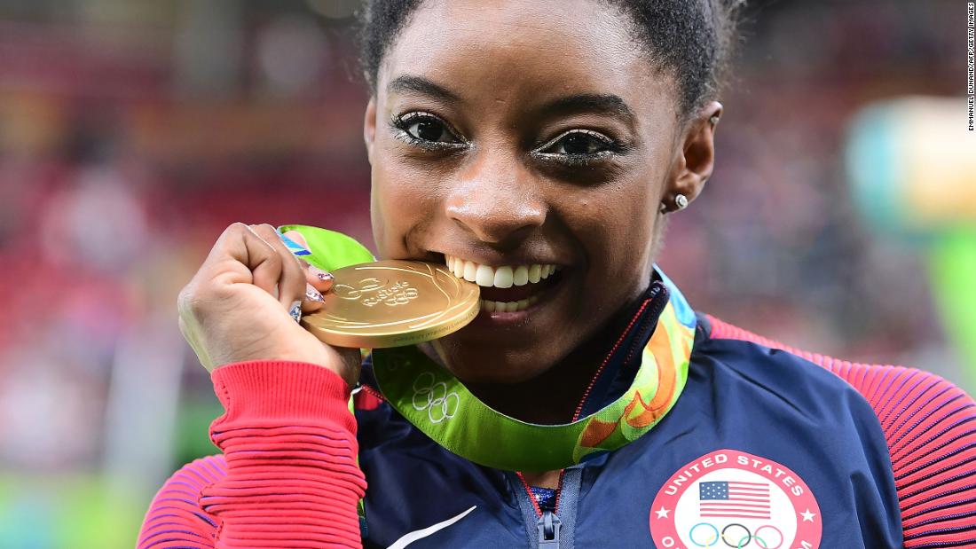 Biles celebrates with the gold medal she earned for her individual all-around title at the 2016 Olympics.