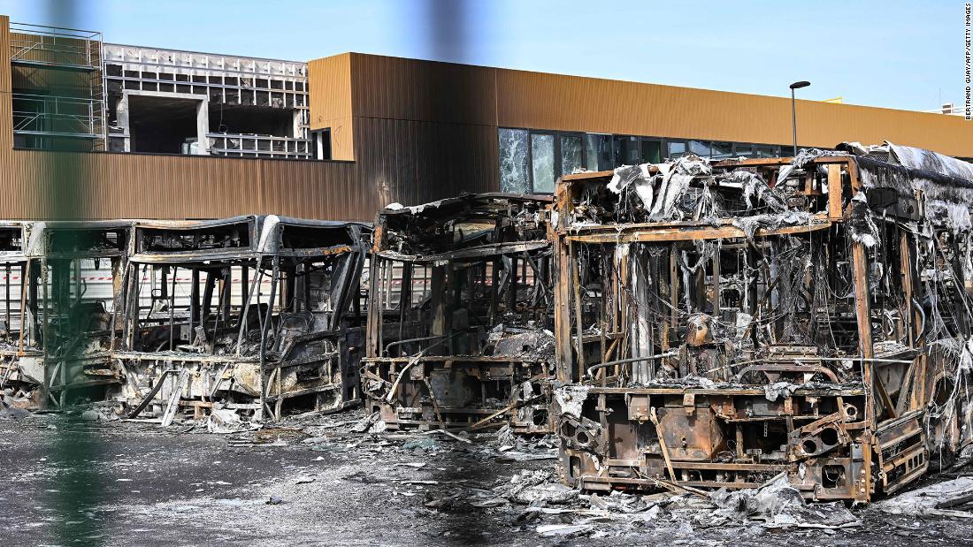Burnt buses can be seen through the gates at the Fort d&#39;Aubervilliers bus terminal in Aubervilliers, France, on June 30.