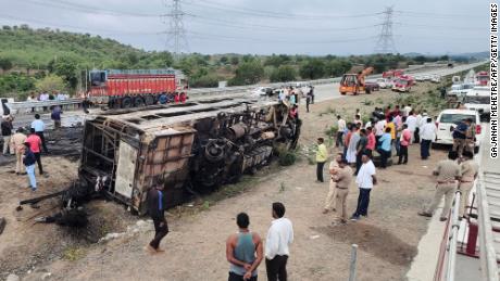 People gather around the wreckage of a bus that caught fire along the Samruddhi Mahamarg expressway near Sindkhed Raja in the Buldhana district of Maharashtra state, India, on July 1, 2023.