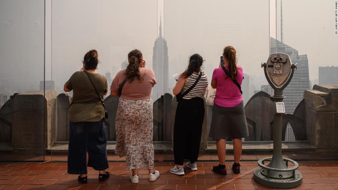 People look out at a hazy Manhattan skyline from the Rockefeller Center viewing deck Friday, June 30, in New York.