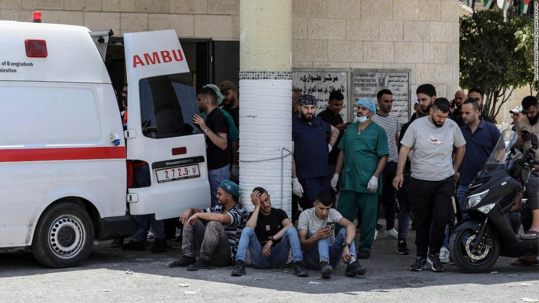 Palestinians wait outside a hospital in Jenin while paramedics transport injured people on Monday.