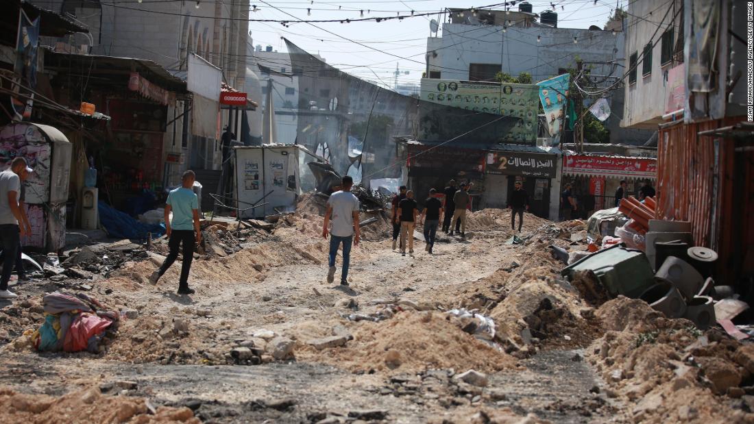 Palestinians walk on the damaged streets of Jenin.