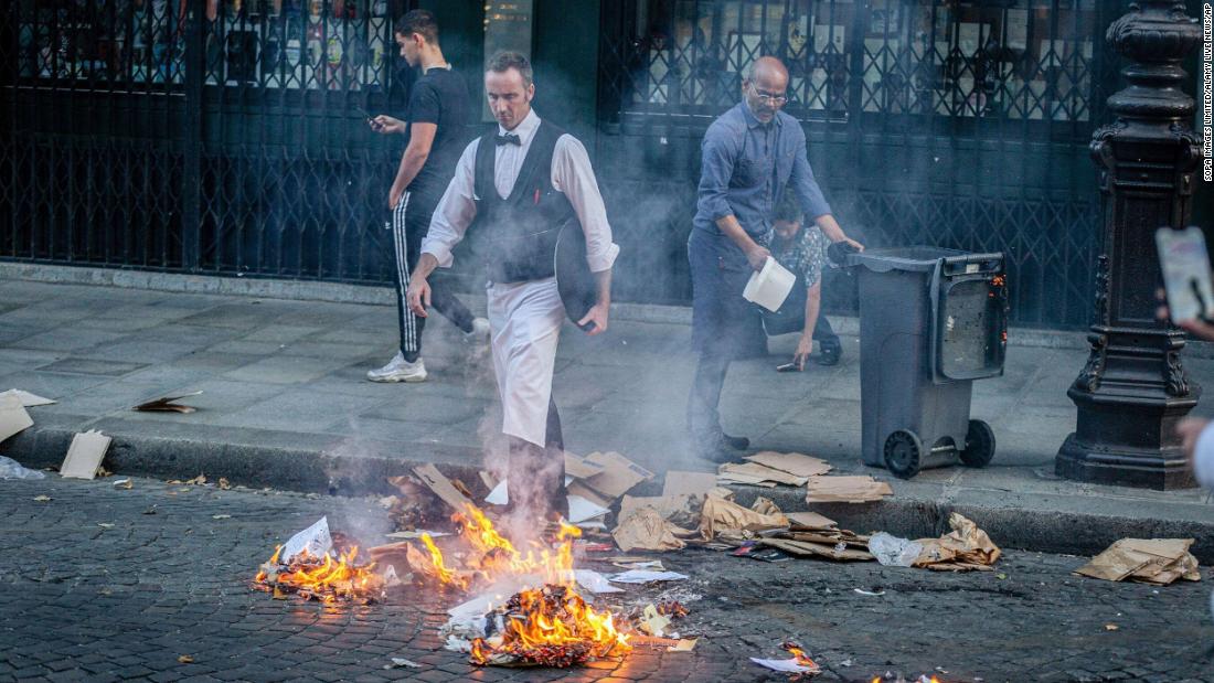 Two restaurant employees extinguish a fire set by demonstrators in Paris on June 30. 