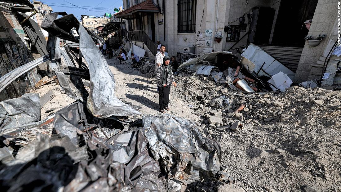 Palestinians are surrounded by rubble and the remains of a destroyed vehicle outside a mosque in Jenin, West Bank, on Wednesday, July 5.