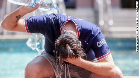 A young man throws a bottle of water over himself to combat the heat on 12 July, 2022 in Madrid, Spain. 