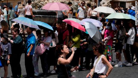 Tourists use umbrellas to shelter from the sun as they line up to enter the Pantheon in Rome, July 8, 2023.