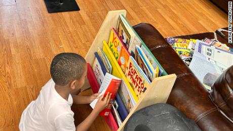 A child selects a book from a barbershop shelf as part of CNN Hero Alvin Irby&#39;s program.