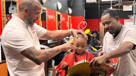 CNN Hero Alvin Irby, right, reads with a young boy during his haircut at Mike Murphy&#39;s barbershop in Philadelphia.