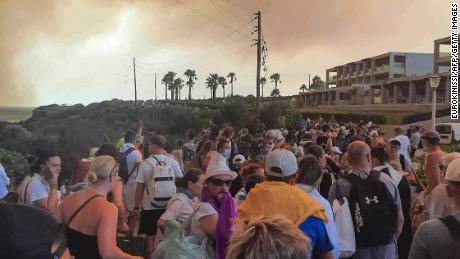 Tourists are evacuated from hotels during a wildfire on the Greek island of Rhodes on July 22, 2023. Three coastguard boats were leading more than 20 vessels in an emergency evacuation effort to rescue people from the Greek island, where fire has been raging out of control for five days. 
