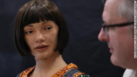 LONDON, ENGLAND - APRIL 04: Ai-Da Robot, an ultra-realistic humanoid robot artist, looks towards Aidan Meller during a press call at The British Library on April 4, 2022 in London, England. Ai-Da will open her solo exhibition LEAPING INTO THE METAVERSE at the Venice Biennale this year curated by Meller. (Photo by Hollie Adams/Getty Images)