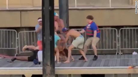 Multiple people stand over and beat a security guard.