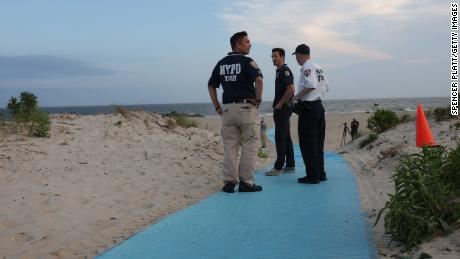 Police gather along Rockaway Beach at 59th Street after a woman was apparently attacked by a shark early Monday evening. 