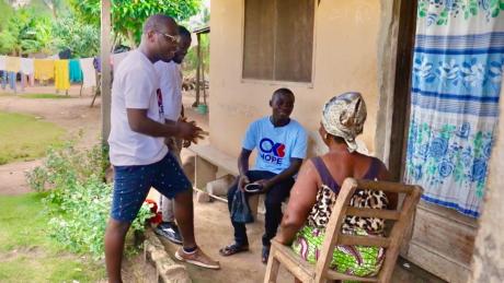 Boateng, left, and two health advocates from his organization check in on a community member.