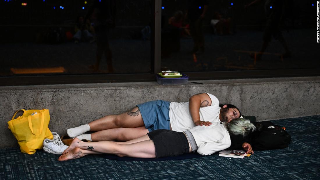 Passengers try to sleep on the floor of the Kahului Airport while waiting for flights on August 9.